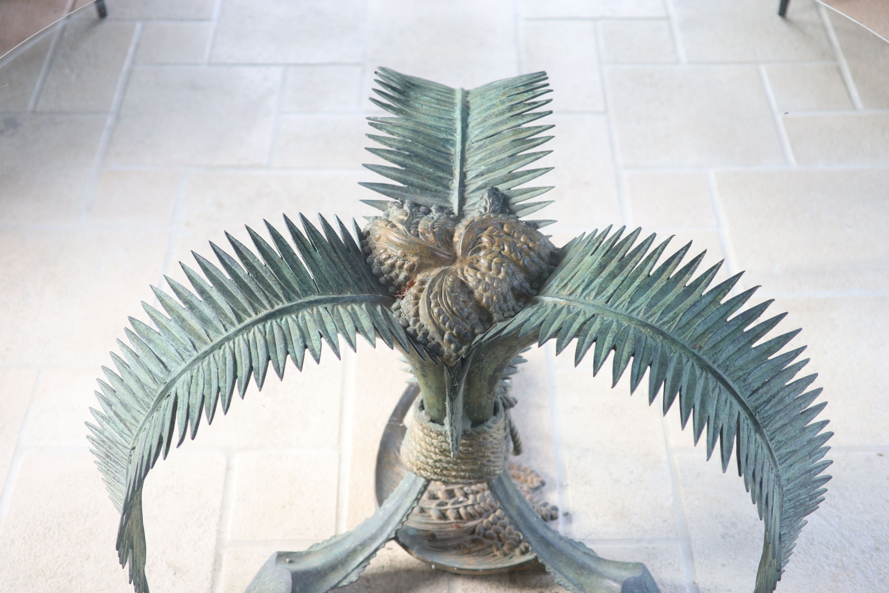 A patinated bronze and glass palm leaf centre table, the circular top 165cm height 75cm